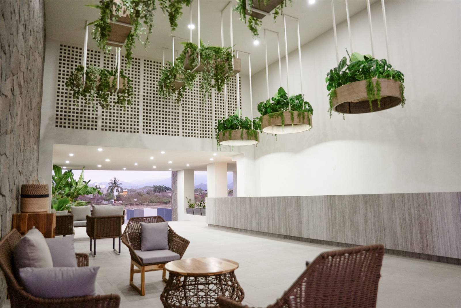 Avenir Armonia Suites: the open lobby with wicker furniture and hanging plants